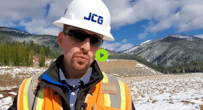 A worker with a mountain behind him.