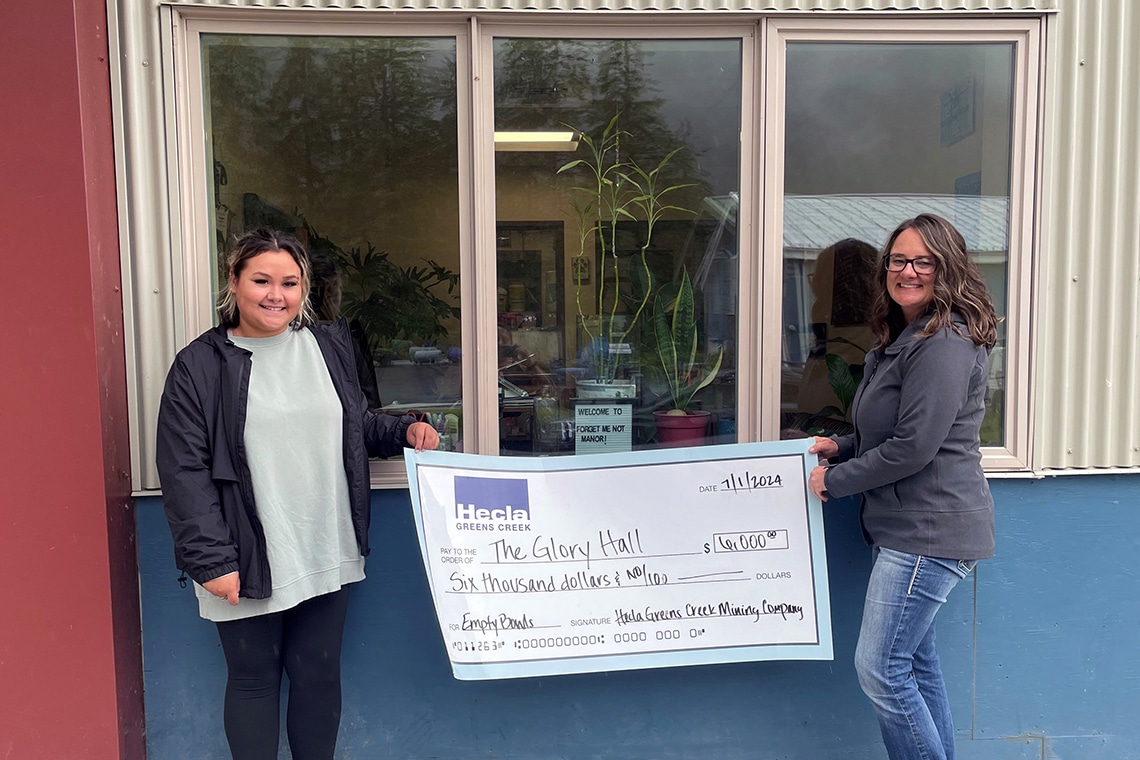 two women holding a giant check made out to The Glory Hall